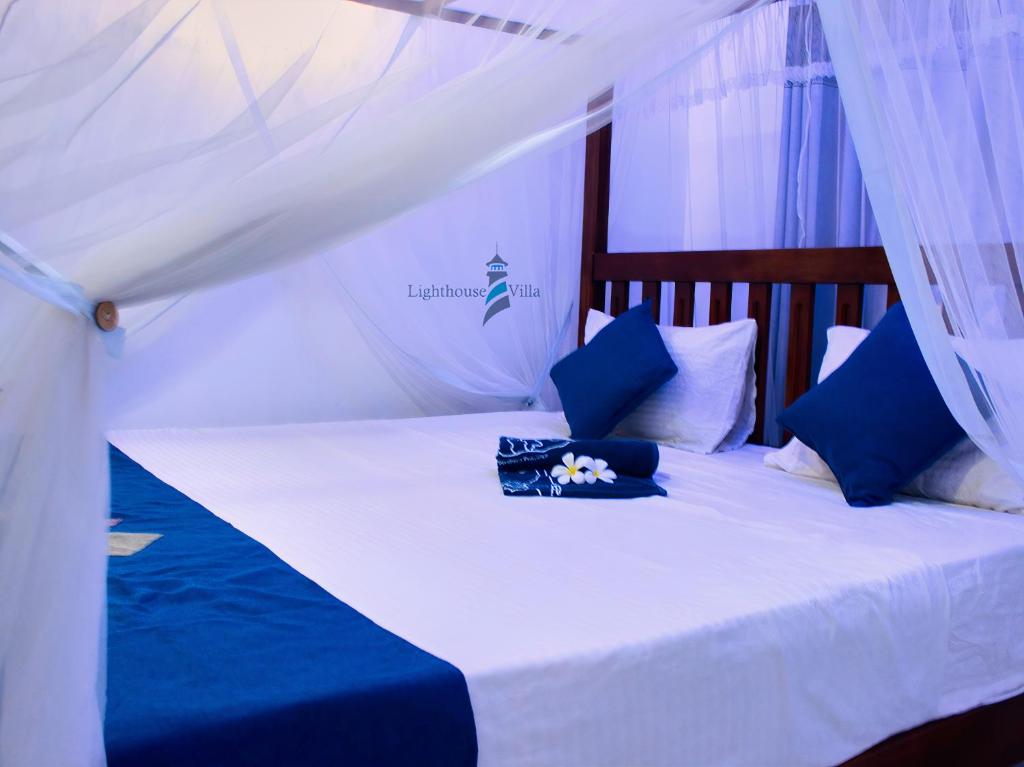 高尔Lighthouse Villa Koggala的一张带蓝色和白色枕头的床和天蓬