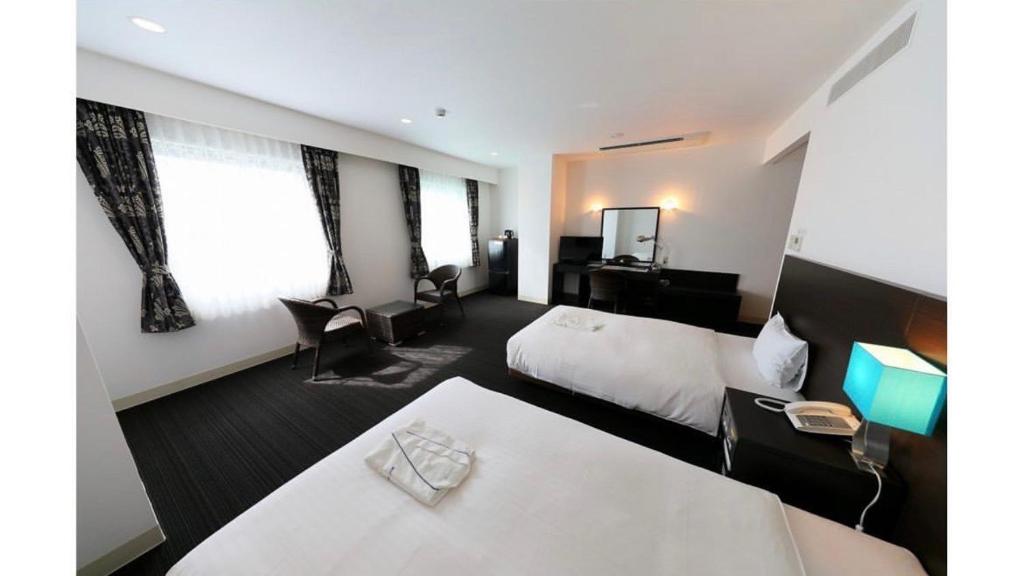 濑户内町奄美里贝斯特酒店的酒店客房配有两张床和一张书桌