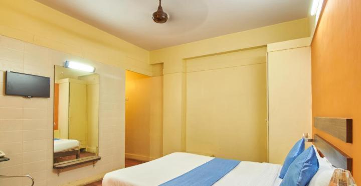 孟买HOTEL GOLDEN PALACE PVT LTD的一间卧室配有一张带镜子的床和一台电视