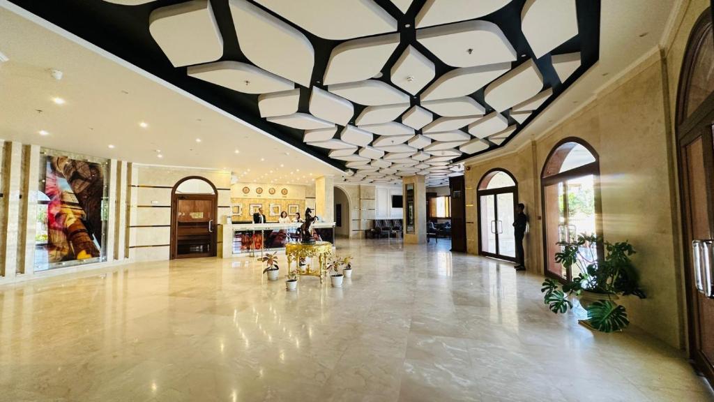 Al KhārijahBadr Hotel & Resort El Kharga的大型大堂设有格子天花板和大型客房。