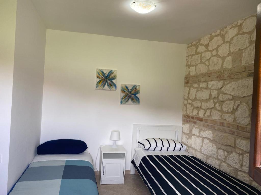 RoccamoricePezzelelle的一间卧室设有两张床和石墙