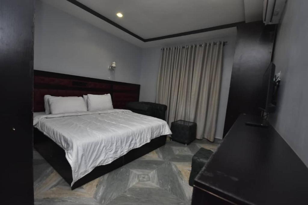 阿奴古La Vista Imperial Hotel的一间卧室配有一张床和一台平面电视