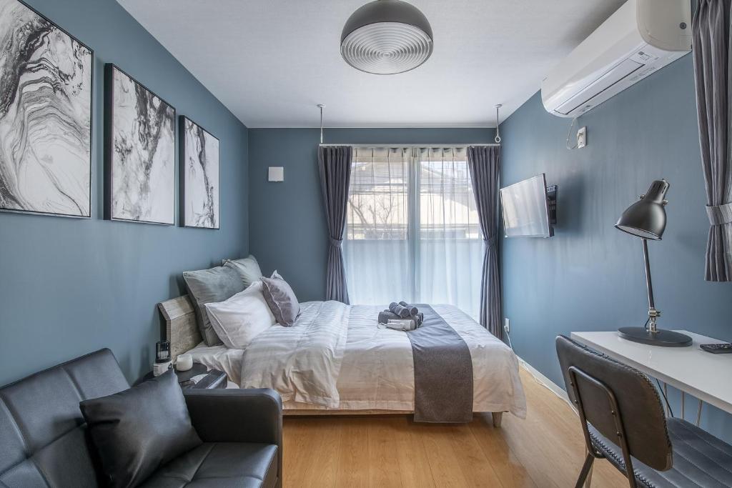 东京Felice Nishi-Shinjuku的蓝色的客房配有床和沙发