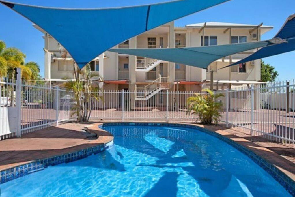 达尔文Sunset Stay的一个带蓝伞的游泳池和一座建筑