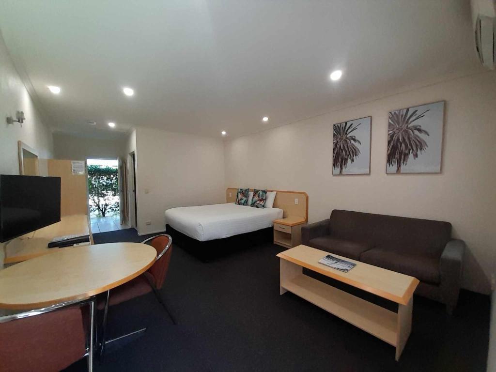 Woombye红桥汽车旅馆的带沙发、床和桌子的客房