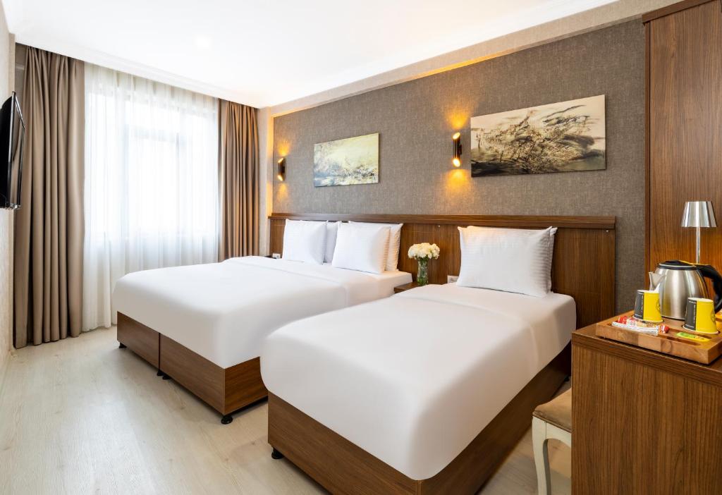 伊斯坦布尔Diamond Beyazit Hotel的配有白色床单的酒店客房内的两张床