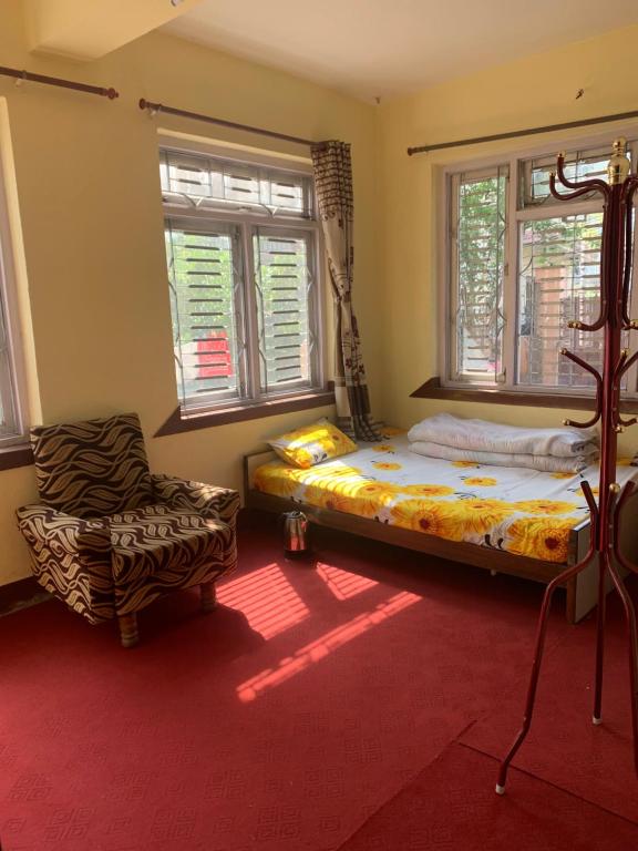 加德满都Osho Gaurishankar Meditation Center的一间卧室配有一张床、一把椅子和窗户。