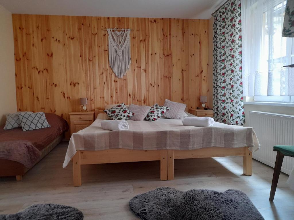 MizernaBodziuchówka的卧室配有一张床铺,位于带木墙的房间内