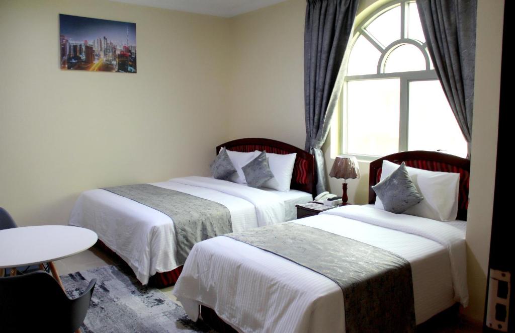 沙迦Al BARAKAH HOTEL的配有窗户的酒店客房内的两张床
