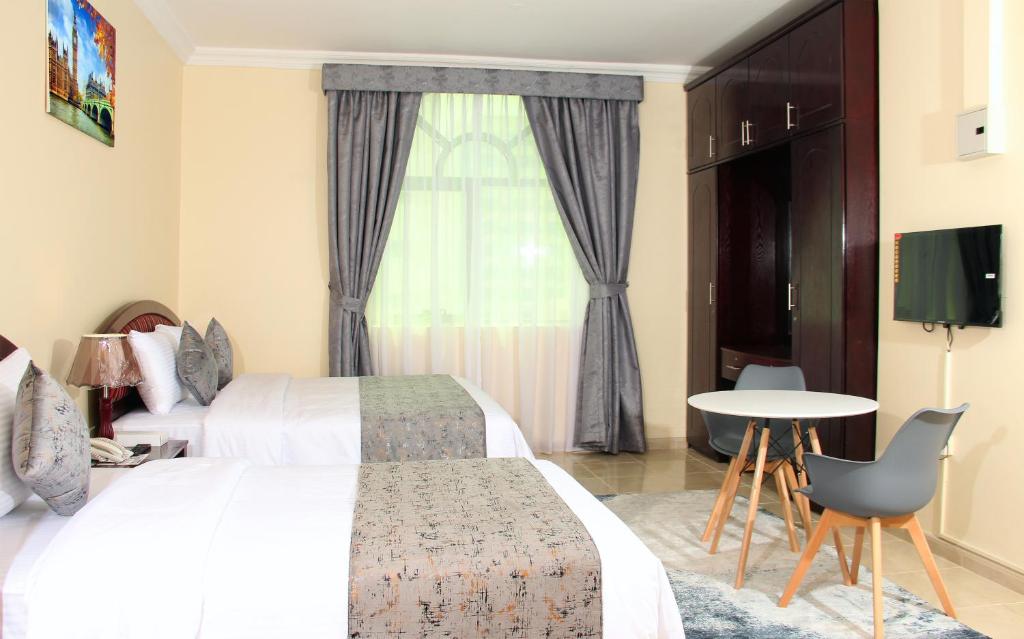 沙迦Al BARAKAH HOTEL的酒店客房设有两张床、一张桌子和一个窗户。
