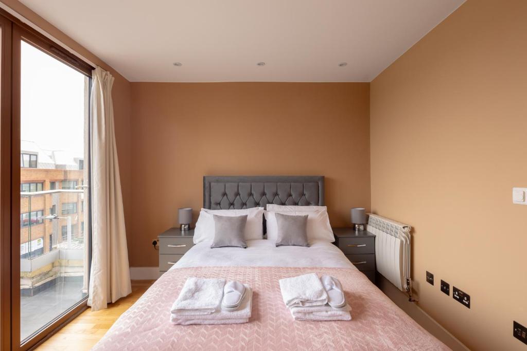 泰晤士河畔金斯顿Charming One-Bedroom Retreat in Kingston KT2, London的一间卧室配有一张大床和两条毛巾