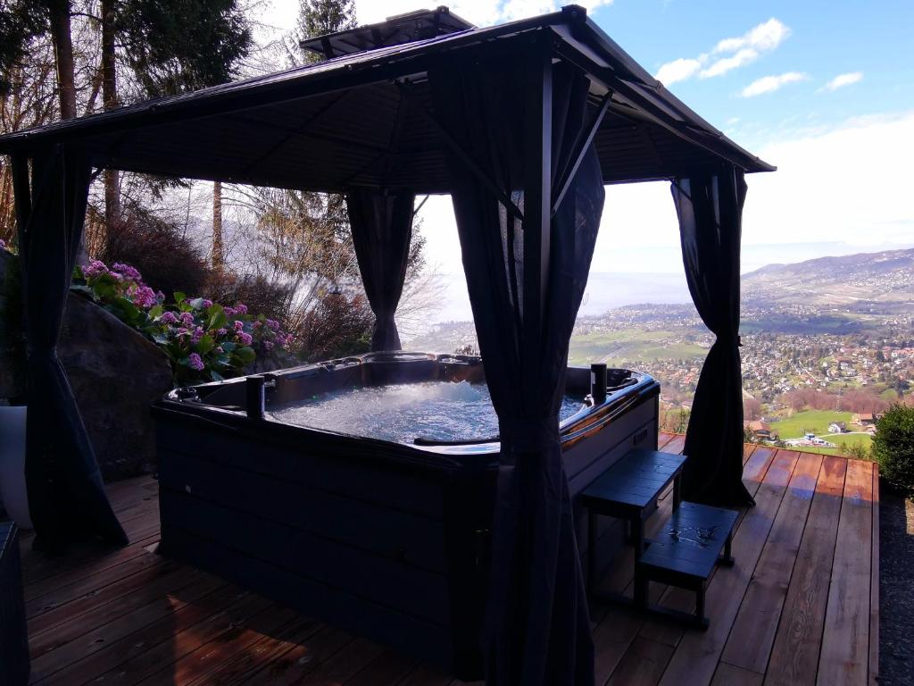 蒙特勒Elvira House Montreux, un lieu magique !的木制甲板上设有1个带天篷的热水浴池