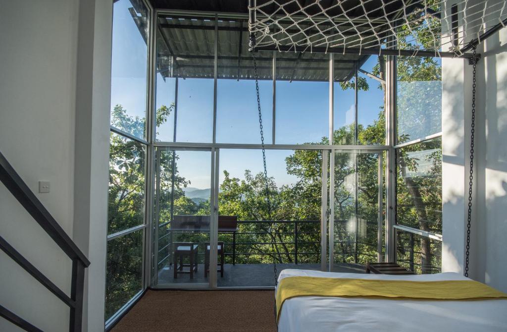 贝里胡罗亚Treehouse Chalets的一间卧室设有一张床和一个大窗户