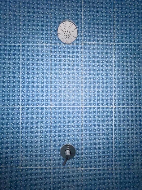 普拉亚TANAWU AIRPORT HOTEL LOMBOK的蓝色瓷砖淋浴间,墙上挂着时钟