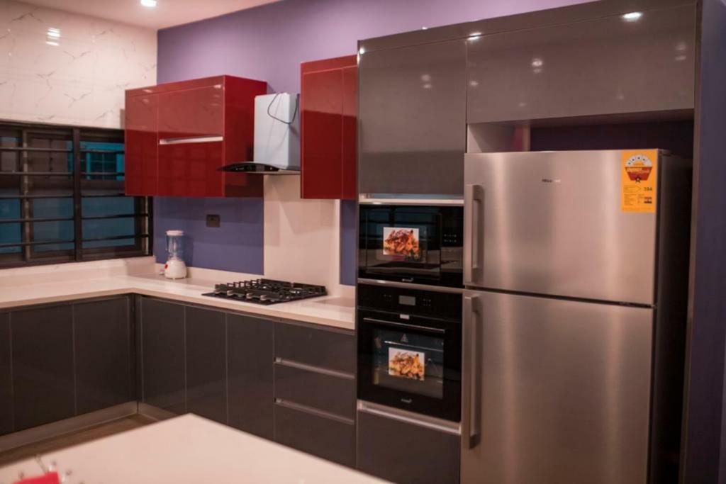 库马西Luxe Vista Villa的厨房配有不锈钢冰箱和红色橱柜