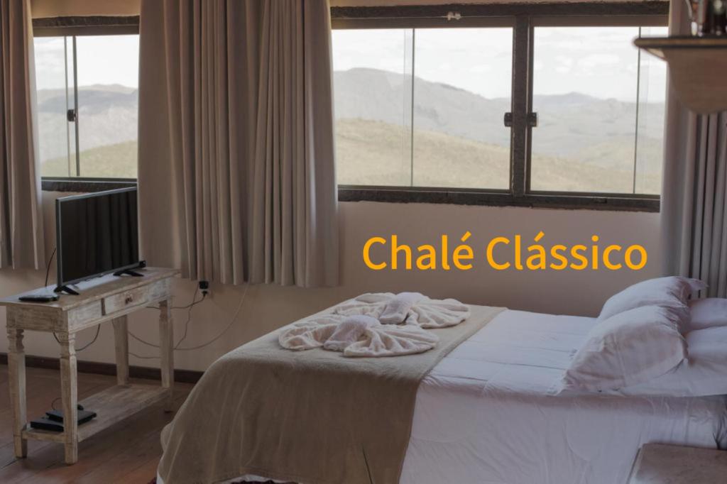 欧鲁普雷图Chalé Mirante do Sol的一间卧室配有一张带书桌的床和窗户。