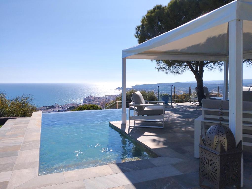 锡切斯Sitges Spaces Sea View Villa- 6 Bedrooms, 5 bathrooms, 2 private pools, Near center的一个带两把椅子的游泳池和一个凉亭