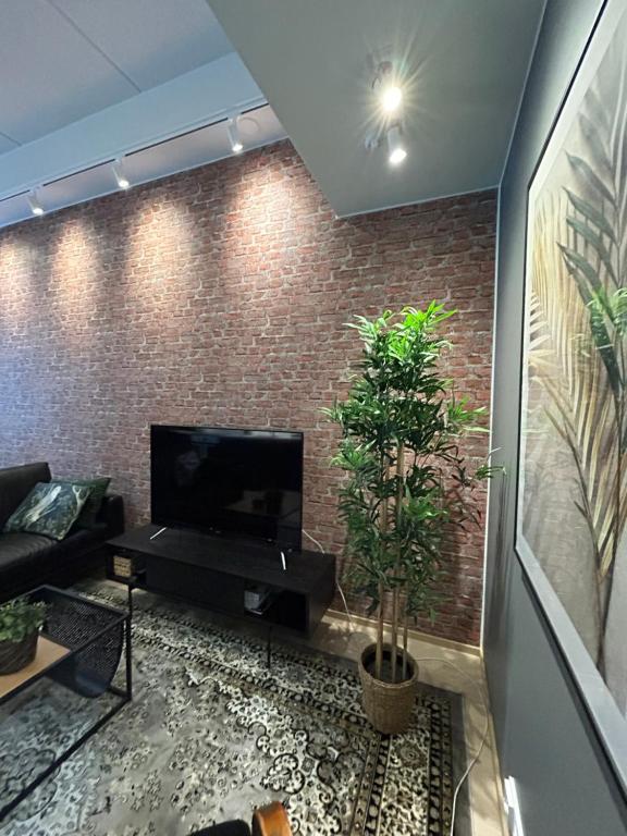 库奥皮奥City Home Alvari, free parking, air conditioning的一间带电视和砖墙的客厅