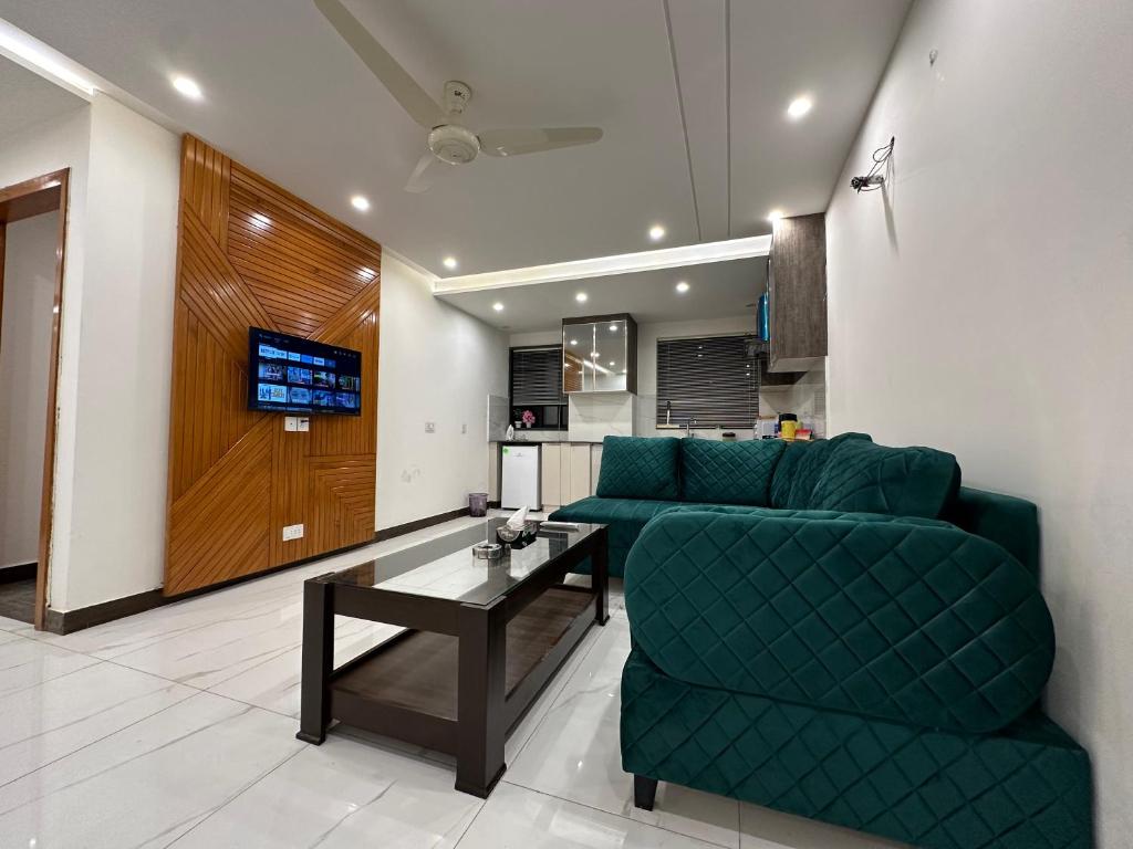 拉合尔Homey Stays - 2 Bedroom Apartment - Gulberg的客厅配有绿色沙发和桌子