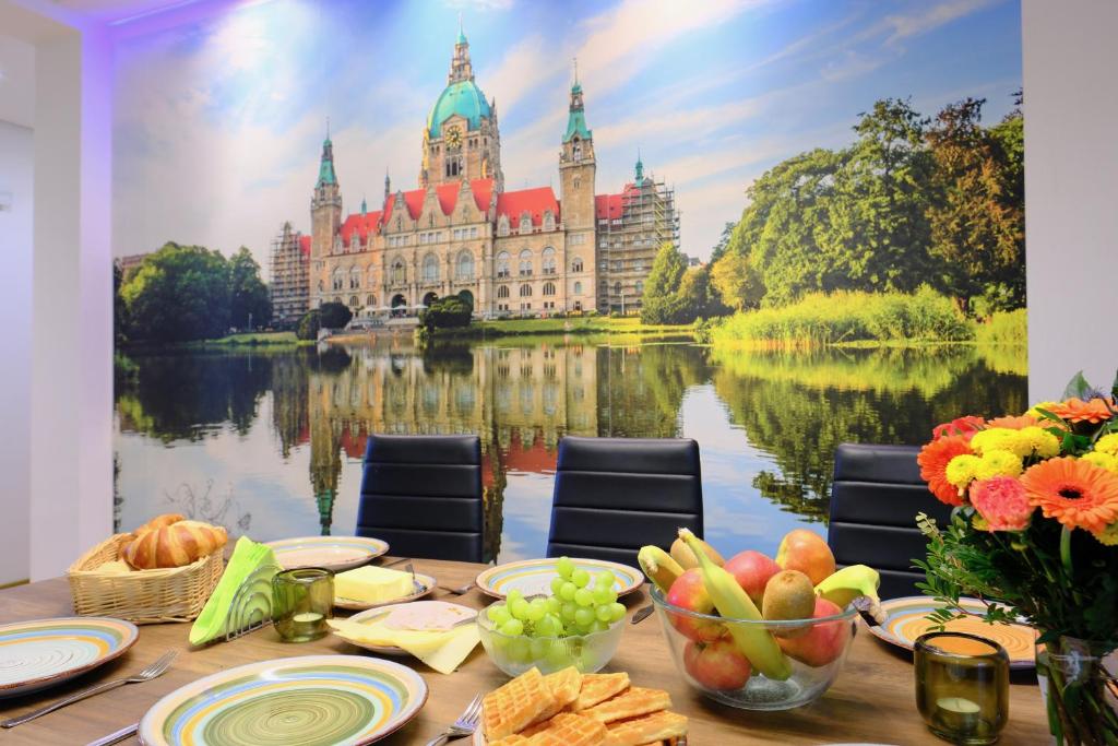 汉诺威HappyBnB - Stilvolles, naturgelegenes Apartment mit Blick auf den Mittellandkanal und die Wasserstadt Hannover - Kamin, Parken und Spielplatz的一张桌子,上面有食物,还有一座大楼在水面上