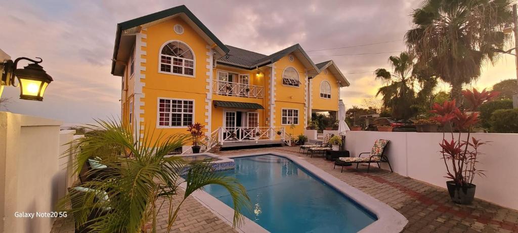 戴蒙德Faith's Villa Tobago的黄色的房子,前面有一个游泳池