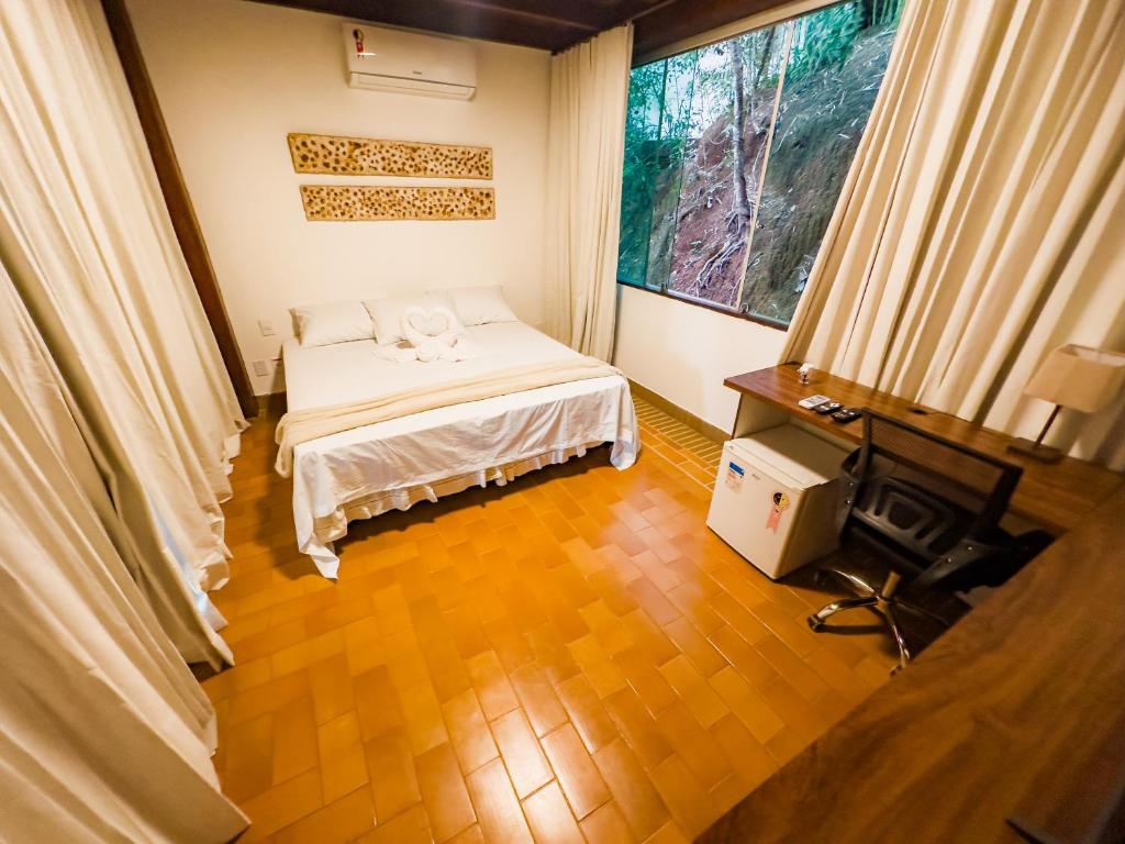 伦索伊斯Pousada Casa de Charme的一间卧室配有一张床、一张书桌和一个窗户。