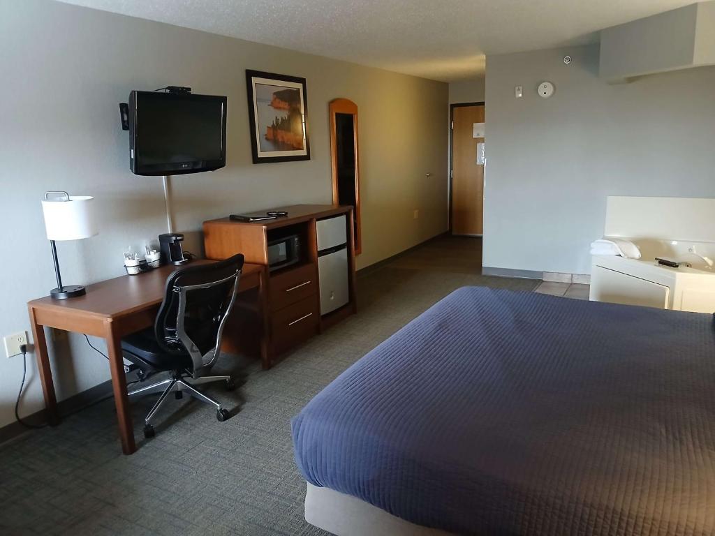 Silver BayBlack Beach Inn by GrandStay的酒店客房配有书桌、床和电视。
