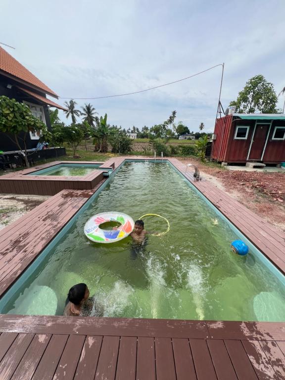 甲抛峇底HOMESTAY Kampong KOTA AUR Resort with swimming pool, Kepala Batas, SEBERANG PERAI, PENANG -MOTAC registered Awarded ASEAN homestay standard Malaysia AWARD 2023-2025 Only 3 minutes from viral KG AGONG的两个孩子在游泳池里玩飞盘