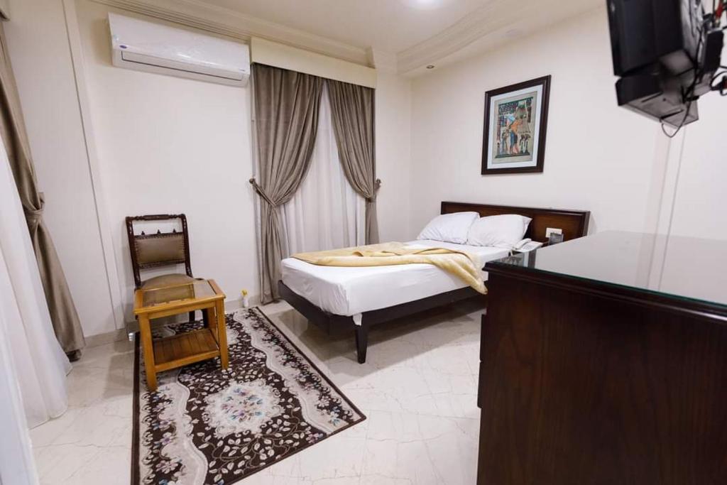 艾斯尤特Badr Hotel Assiut的一间卧室配有一张床、一张桌子和一台电视