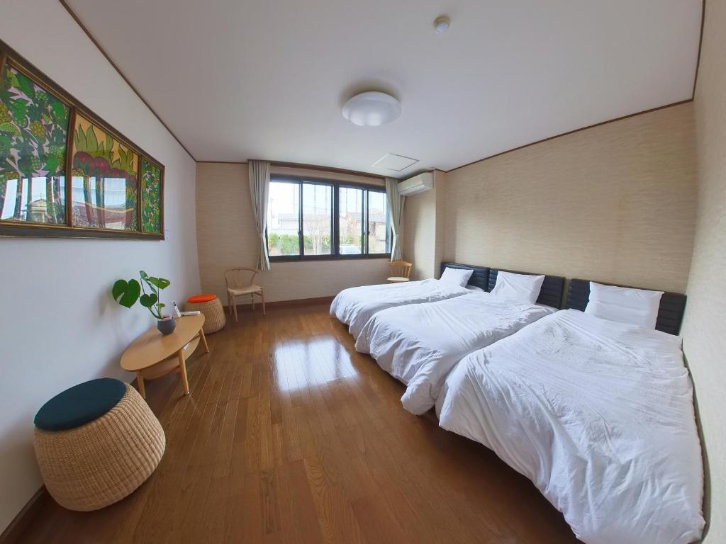 鹤冈市TSURUOKA GINZA 朙 sukima的一间卧室设有两张床、一张桌子和一个窗口
