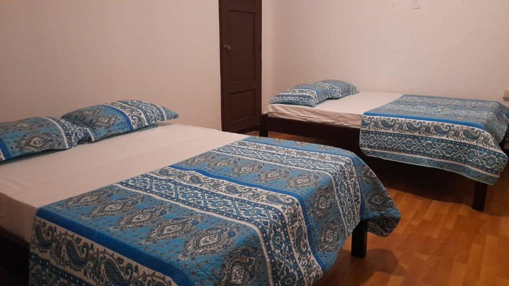 El VenadoHotel Sansivar的一间设有三张床的房间,配有蓝色和白色的盖子