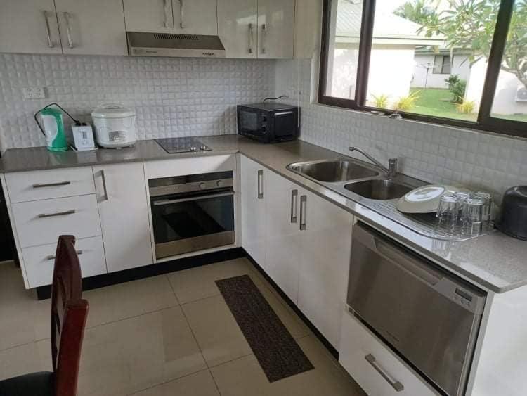 南迪Bula Villas的厨房配有白色橱柜、水槽和炉灶。