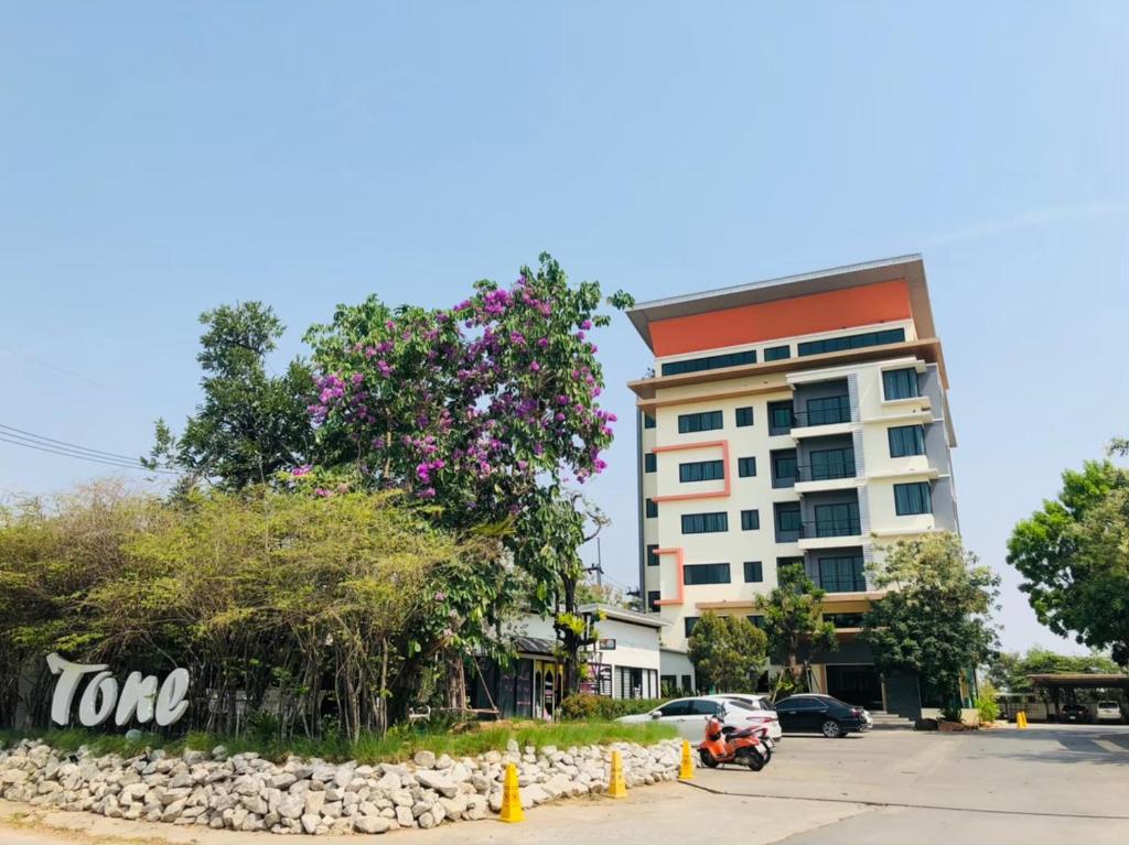 北柳Tone Condorent Hotel的一座建筑,前面有一棵树,上面有粉红色的花朵