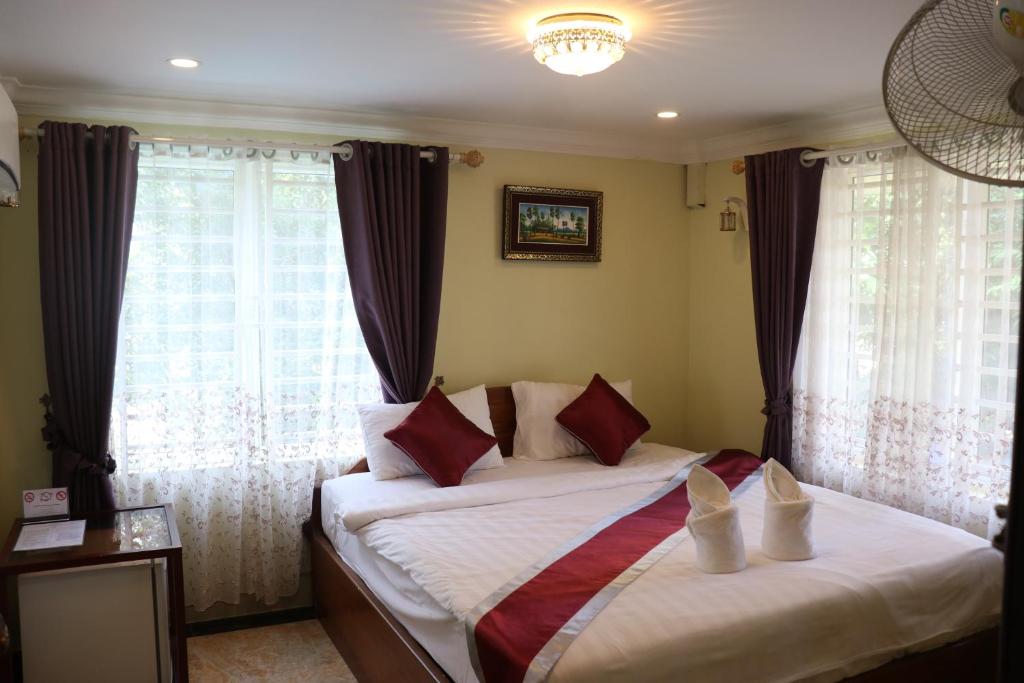贡布AHHA Boutique Kampot的一间卧室配有带白色床单和红色枕头的床。