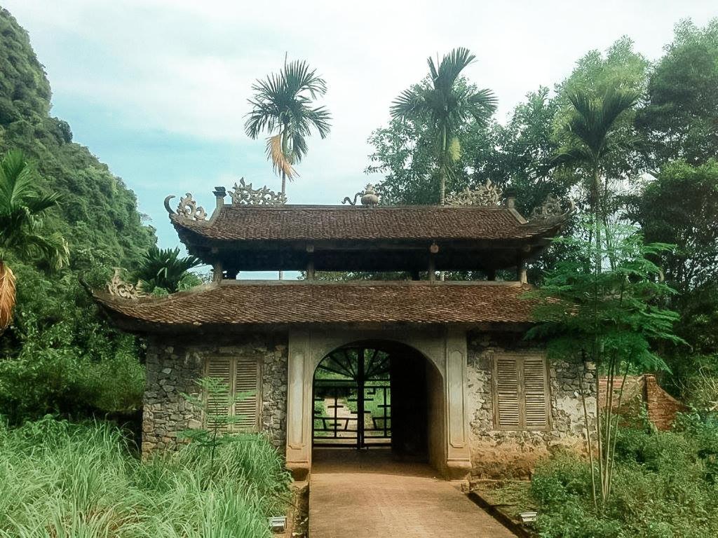 海防Ancient House Cat Ba的一座拥有大门和棕榈树的建筑的入口