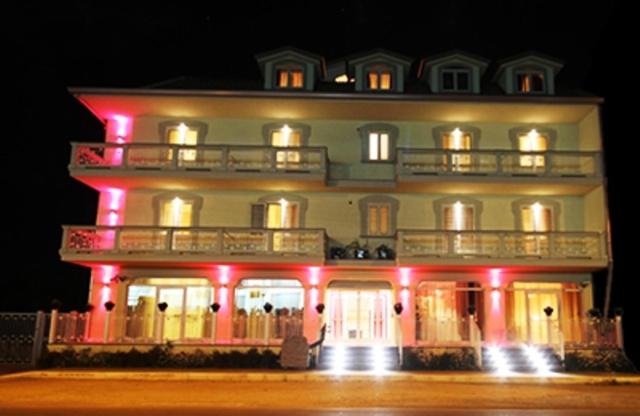 诺切拉泰里内塞乌纳努欧瓦斯特拉达皇宫酒店的一座白色的大建筑,有红灯