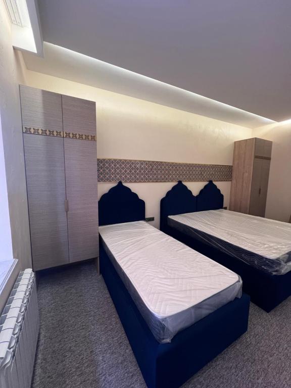 塔什干Hamsa Butique Hotel Tashkent的配有蓝色靠垫的客房内的两张床