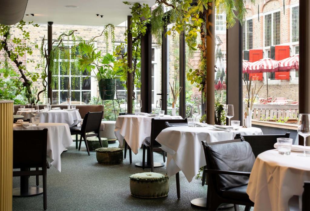 豪达Relais & Châteaux Weeshuis Gouda的餐厅设有白色的桌椅和窗户。