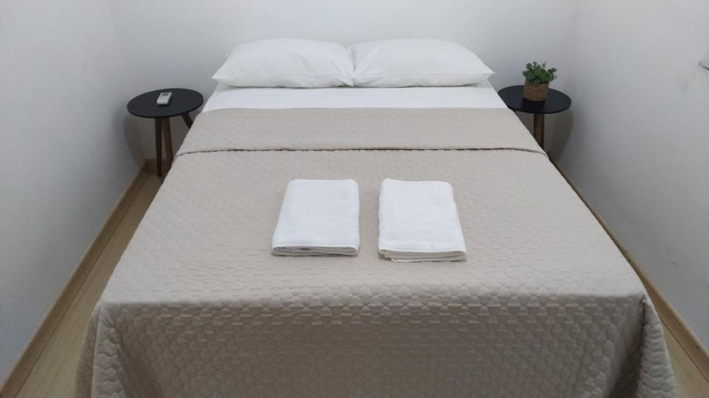 圣安热卢AP Confortável San Inácio的一张带白色床单和毛巾的床