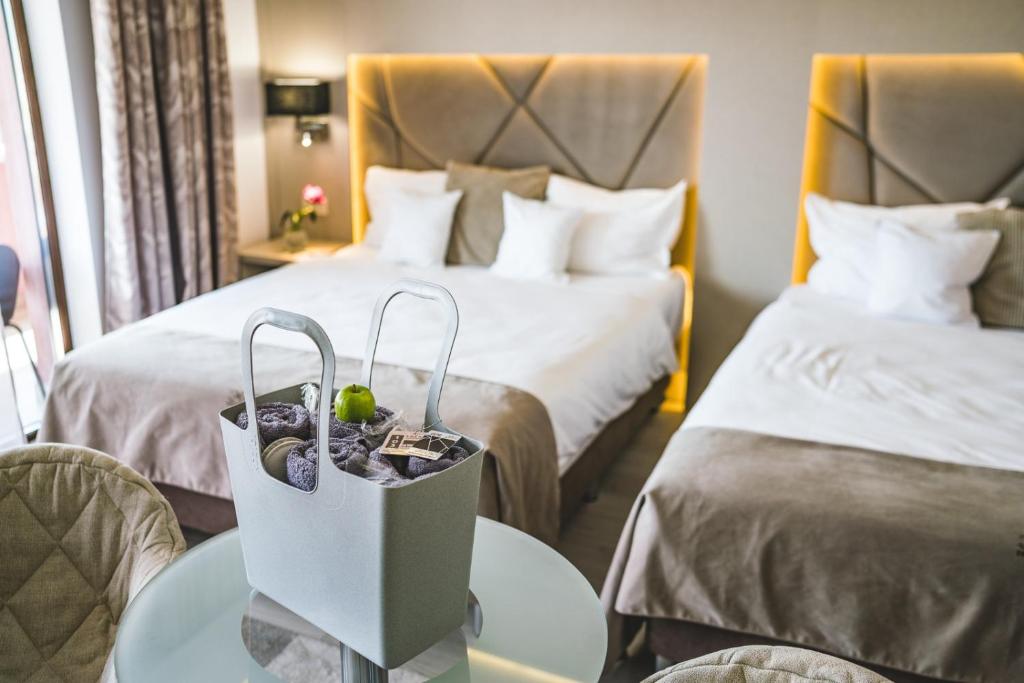 坎普朗莫道尼斯Hotel Eden Garden Spa的酒店客房设有两张床和一张带袋子的桌子
