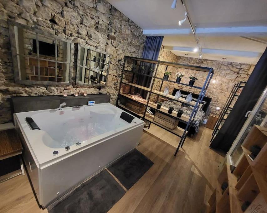 塞特港Balnéo Room, Loft Déco Authentique, Jacuzzi, Centre, Climatisation的石墙客房内的大浴缸