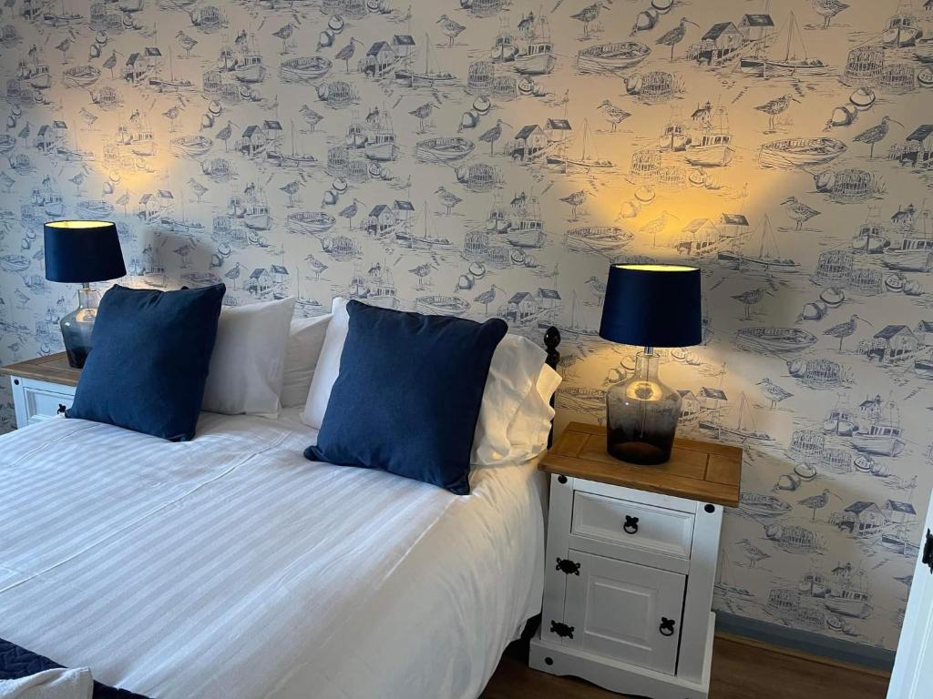 杜伦Durham City Cottages的一间卧室配有一张带蓝色枕头的床和两盏灯。