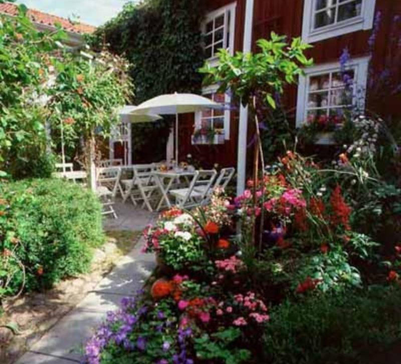 阿斯克松德Garvaregården Hotel , B&B och Café的一座花园,在房子前种有鲜花