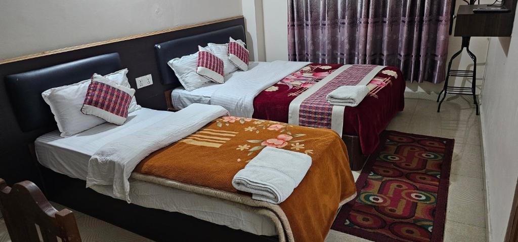 西玛拉Hotel Simara的两张睡床彼此相邻,位于一个房间里