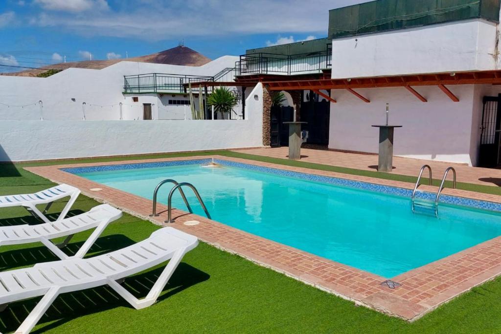 阿雷西费Lanzarote Hostel的一个带两把草坪椅的游泳池