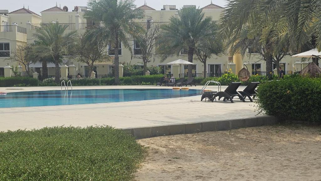 拉斯阿尔卡麦Luxury villa 4 bedroom with pool access的一座带椅子和桌子的游泳池位于大楼旁