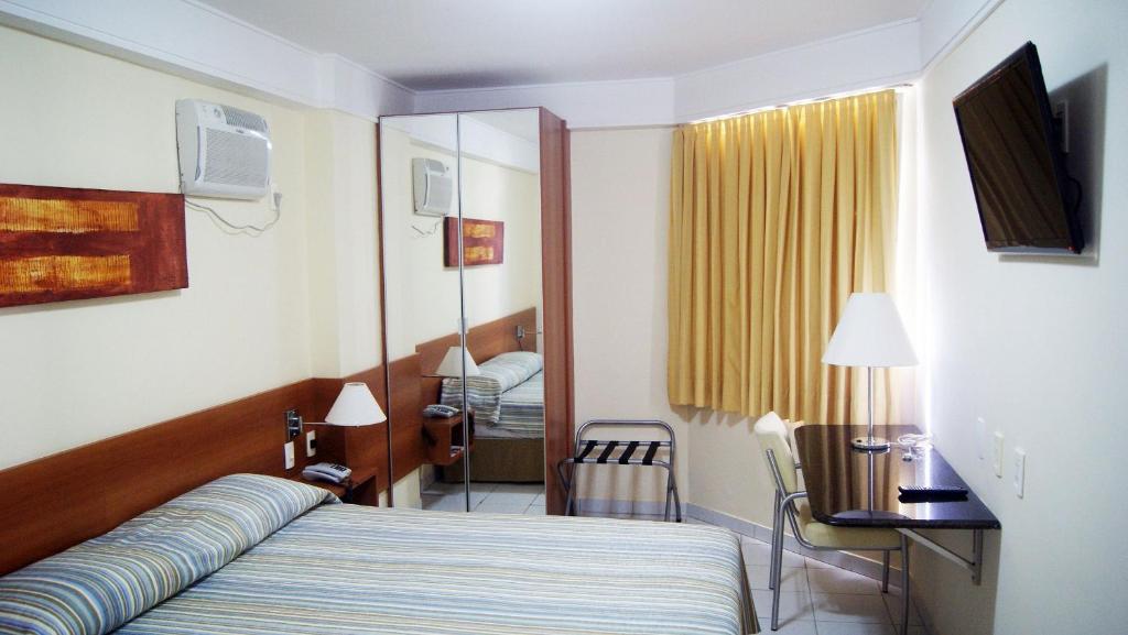 纳塔尔CJC Short Stay Natal的一间卧室配有一张床、一张书桌和一面镜子