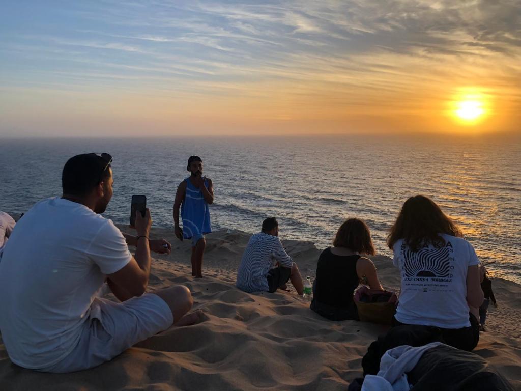 依索安Oceana surf house的一群坐在海滩上的人,看着日落