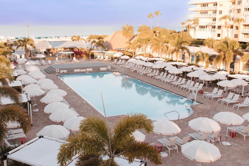 圣徒皮特海滩海滩明信片旅馆的一个带白色遮阳伞和桌椅的游泳池