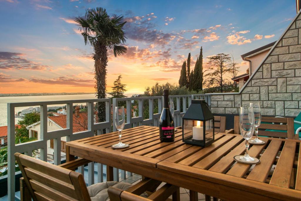 波尔托罗ARIA Superior Apartment, Seaview & Wellness的阳台上配有带酒杯和蜡烛的木桌